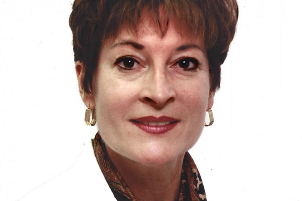 A woman wearing a doctor's white coat poses for a photo.