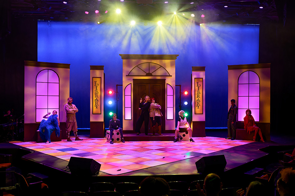 Students onstage in colorful costumes and lights