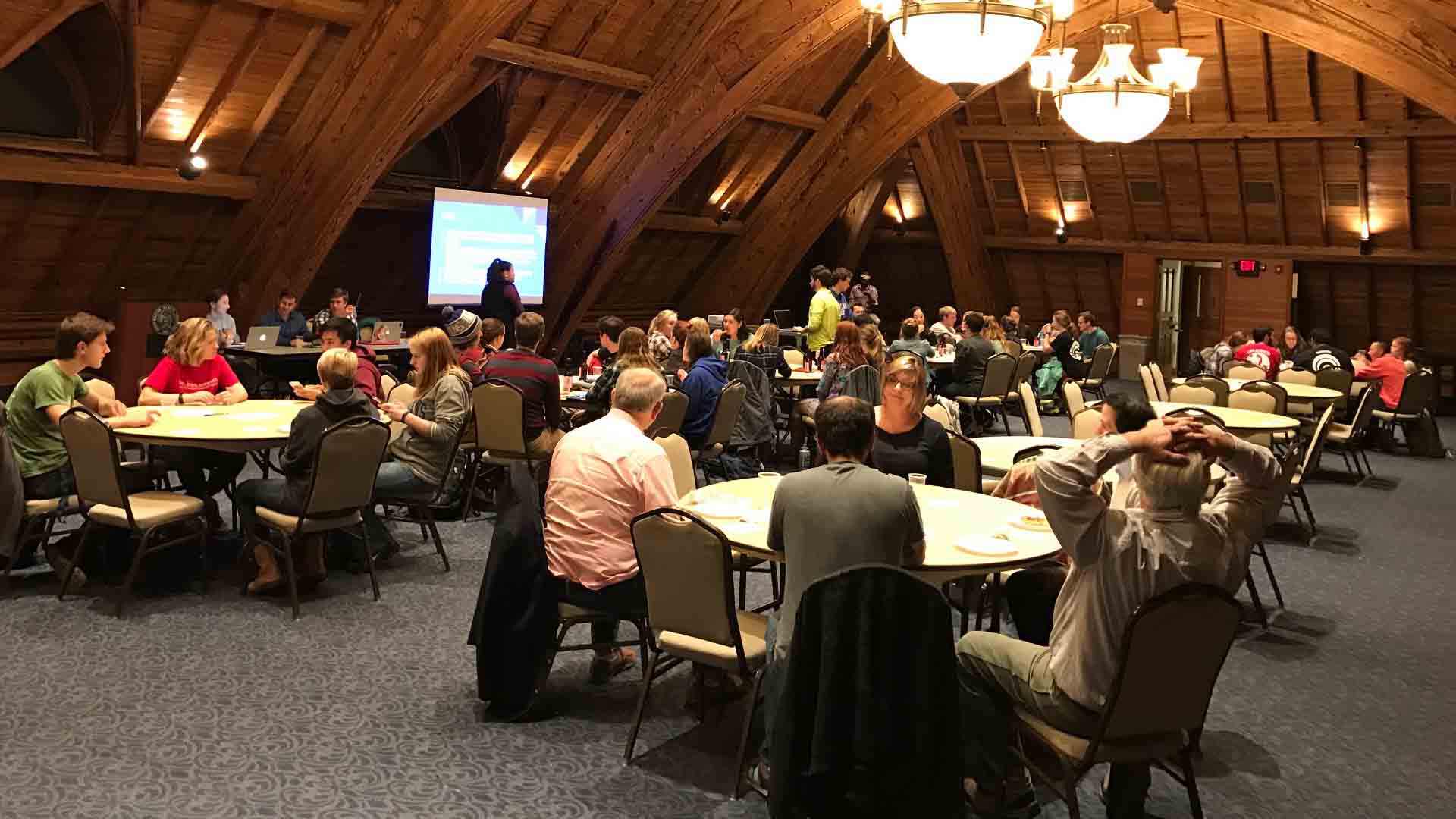 Students, facult and guests sit at tables for trivia night