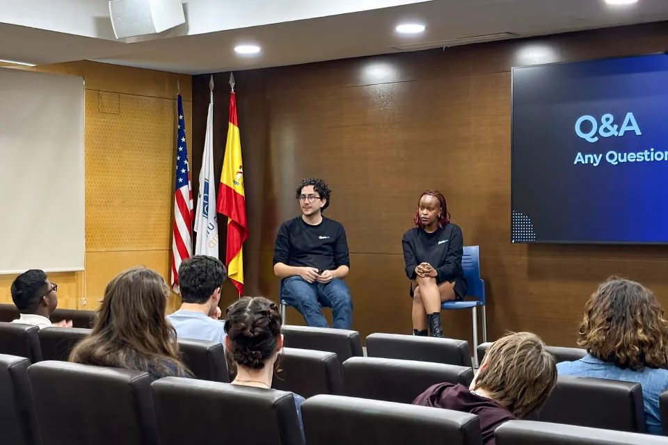 Applylab Founder Speaks at SLU-Madrid on Landing Internships Guest speaker and a panelist sit at the front of the auditorium facing students seated in the audience with U.S., Spanish and university flags visible behind them and a presentation slide reading "Q&A – Any Questions."
