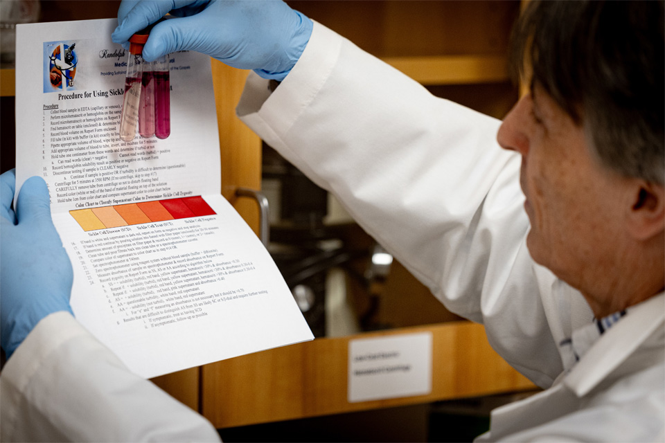 A photo of a researching handling vials of specimens