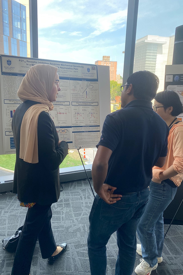 Two attendees hold a discussion in front of a research poster.